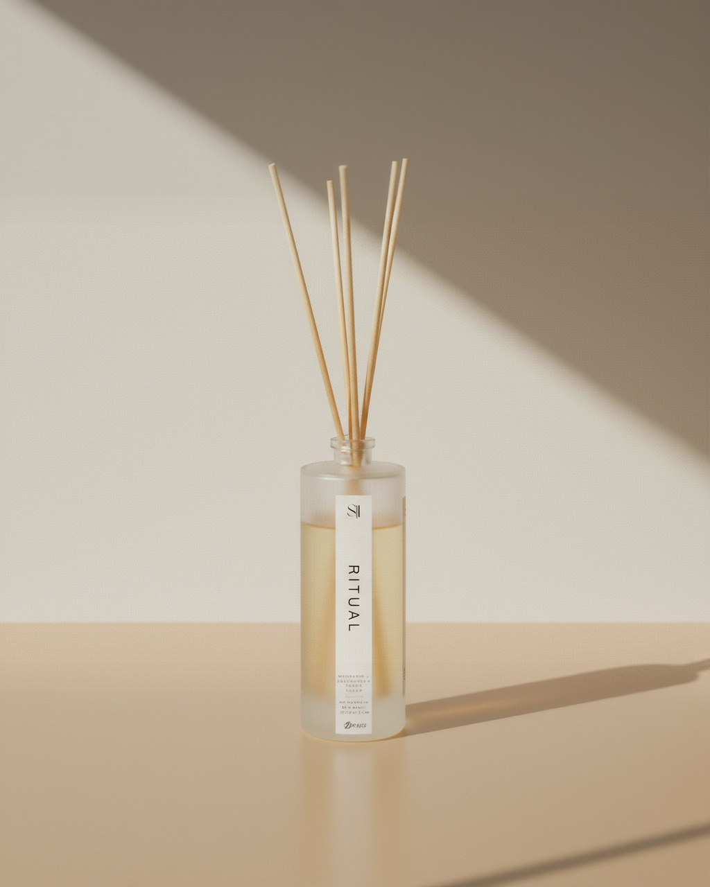 Reed diffuser with wooden sticks in a clear bottle on a beige surface
