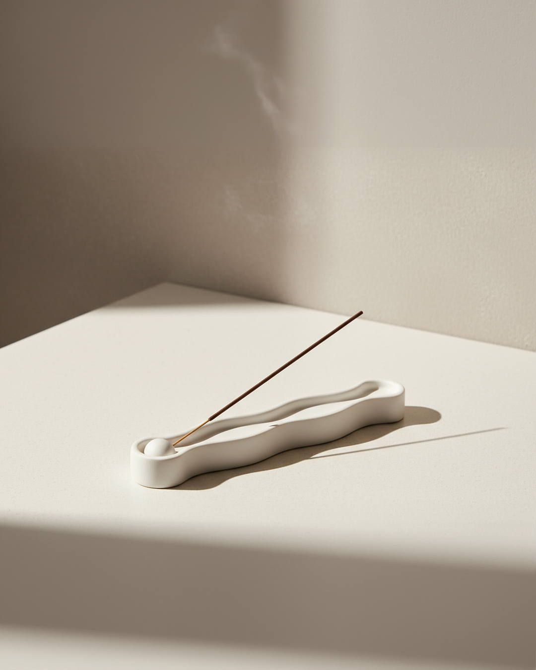 White ceramic incense holder with a single incense stick on a beige surface.